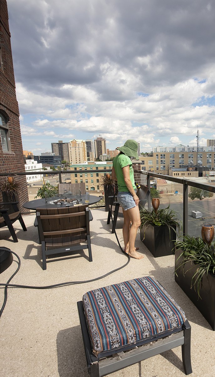 Woman watering plants on a rooftop patio